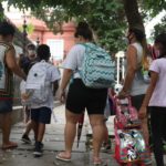 adultas acompanham crianças com uniformes escolares e mochilas a caminho da escola; A política de creches brasileira é um exemplo de ação pública baseada na transversalidade de gênero, pois considera a divisão sexual do trabalho, diz estudo da FGV.